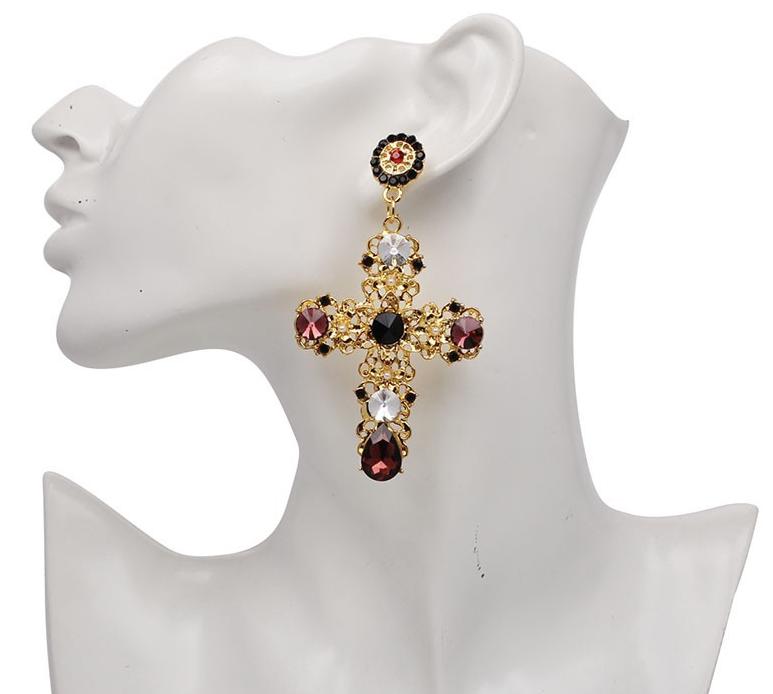 A gold coloured filigree cross with crystal embellishments and tiny faux pearl flower pieces.