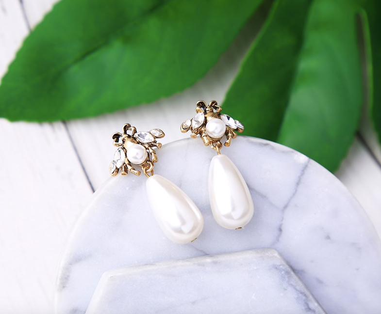 A small and detailed bug stud in vintage gold, faux pearl and clear crystals, complimented by a large faux pearl drop.