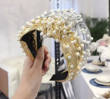 This statement piece exudes sophistication, boasting a knotted wide formation detailed with handcrafted simulated pearls placed on either gold or silver synthetic leather. Perfect for race day chic or a relaxed weekend style, these luxe headbands complete any look.