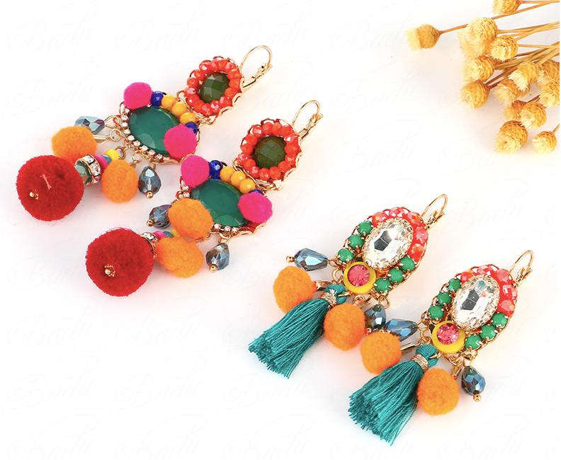 A smaller tassel earring bosting pom pom's and crystal in vibrant greens, pinks, blues and oranges in a classic set earring.  Small resin studs centered around a larger clear crystal with pom poms and a tassel at the bottom. Lightweight.