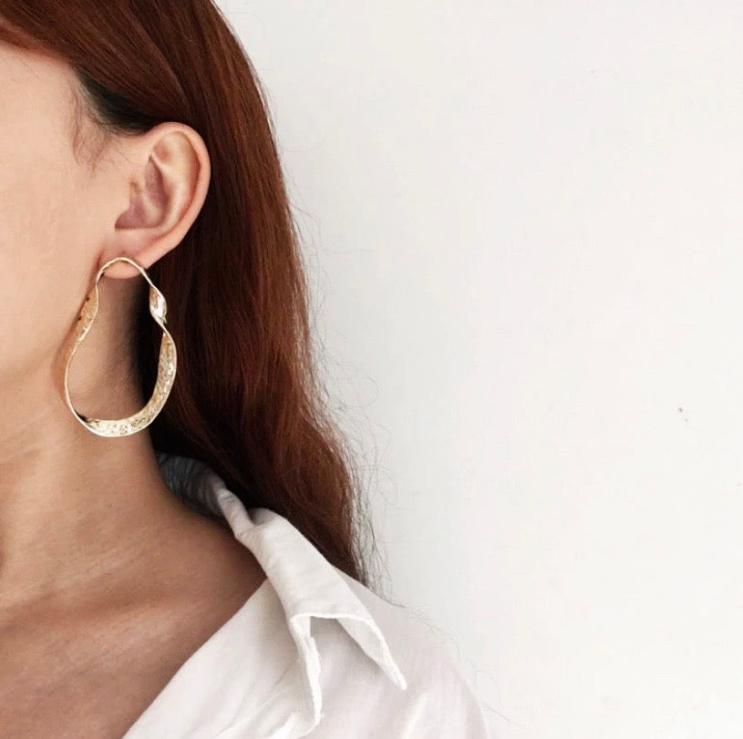 A twisted oblong oversized hoop in gold or silver.