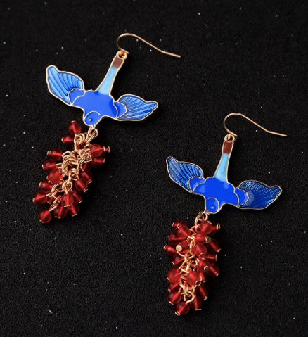 A beautiful blue enamel bird with wings spread and holding a gorgeous bunch of red resin beads from its beak. Framed in vintage gold. Lightweight and unique.