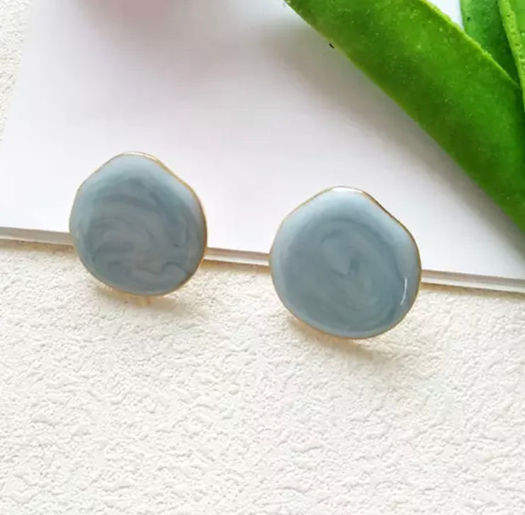 A simple, medium sized flat stud with a drip texture and fine gold trim.