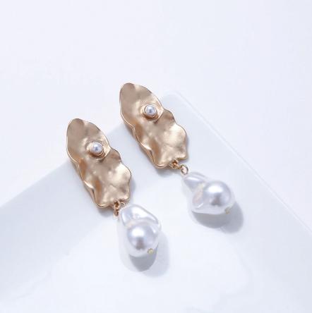 A generous sized pearl like drop attached to an abstract gold plate. 