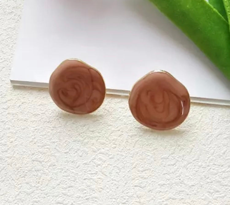 A simple, medium sized flat stud with a drip texture and fine gold trim.