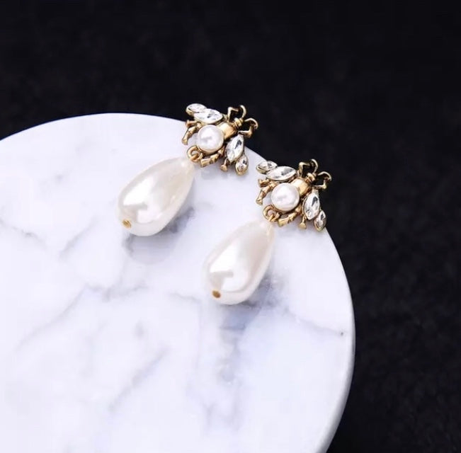A small and detailed bug stud in vintage gold, faux pearl and clear crystals, complimented by a large faux pearl drop.