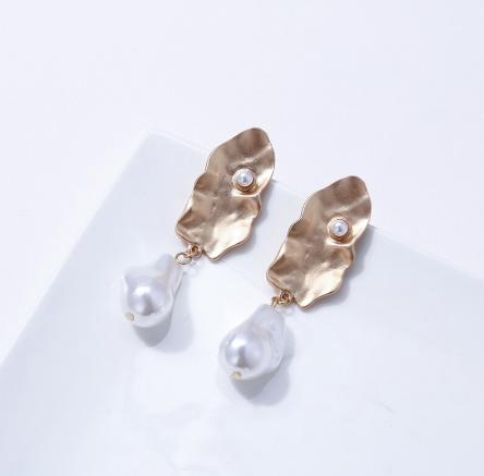 A generous sized pearl like drop attached to an abstract gold plate. 