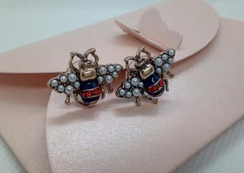 A small bug stud with a navy and red body, pearl encrusted wings and gold framing. The detailing on these little bugs is just gorgeous. 