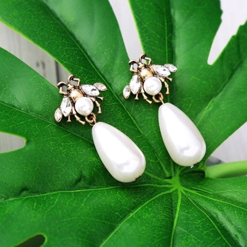 A small and detailed bug stud in vintage gold, faux pearl and clear crystals, complimented by a large faux pearl drop.