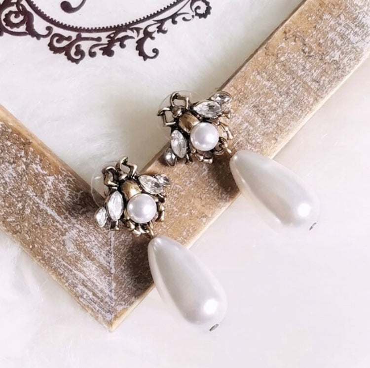 A small and detailed bug stud in vintage gold, faux pearl and clear crystals, complimented by a large faux pearl drop.