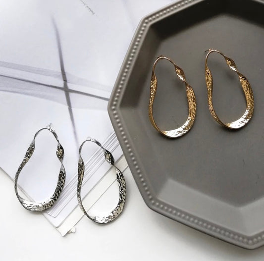 A twisted oblong oversized hoop in gold or silver.