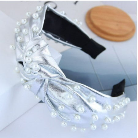 This statement piece exudes sophistication, boasting a knotted wide formation detailed with handcrafted simulated pearls placed on either gold or silver synthetic leather. Perfect for race day chic or a relaxed weekend style, these luxe headbands complete any look.